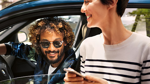 Muž sedí v BMW a žena s chytrým telefonem BMW Financial Services muž sedí v BMW a žena s chytrým telefonem
